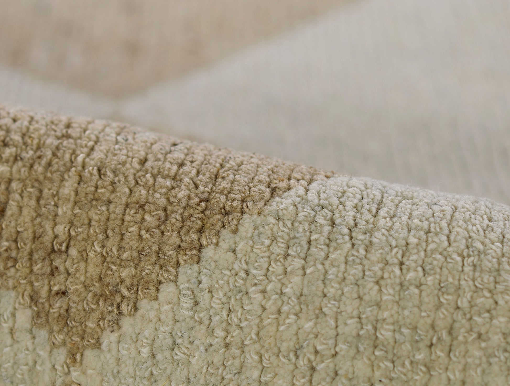 Close-up of a neutral beige boucle rug with soft loop pile in cream and tan tones.