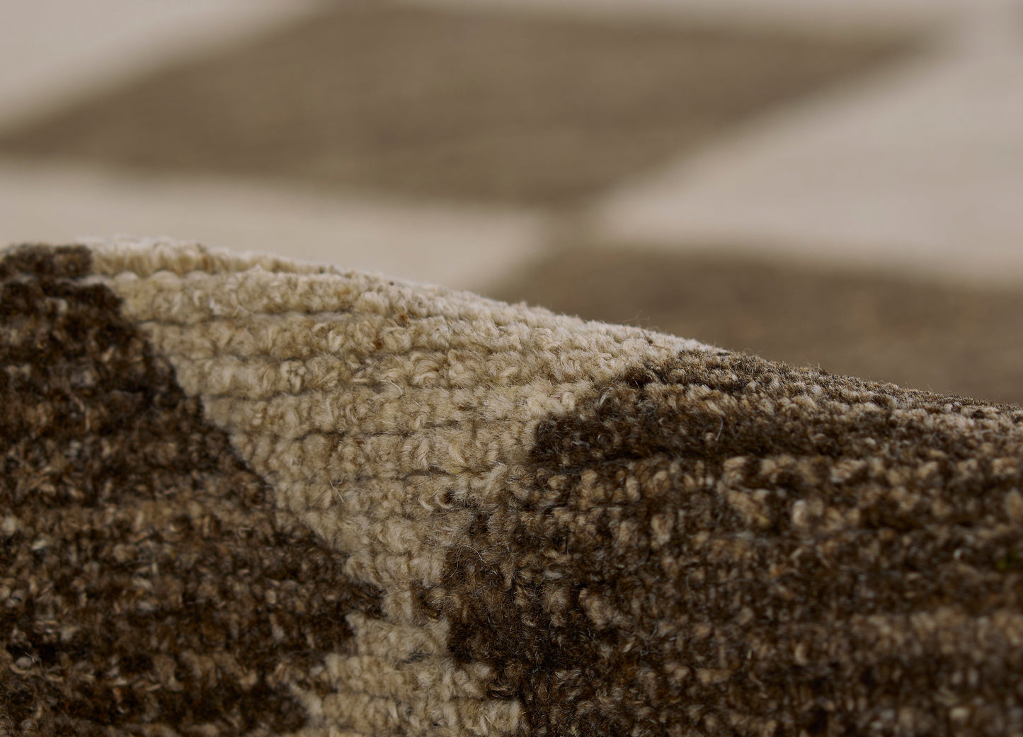 Close-up of a two-tone cream and brown shaggy rug with a geometric pattern and plush tufted pile.