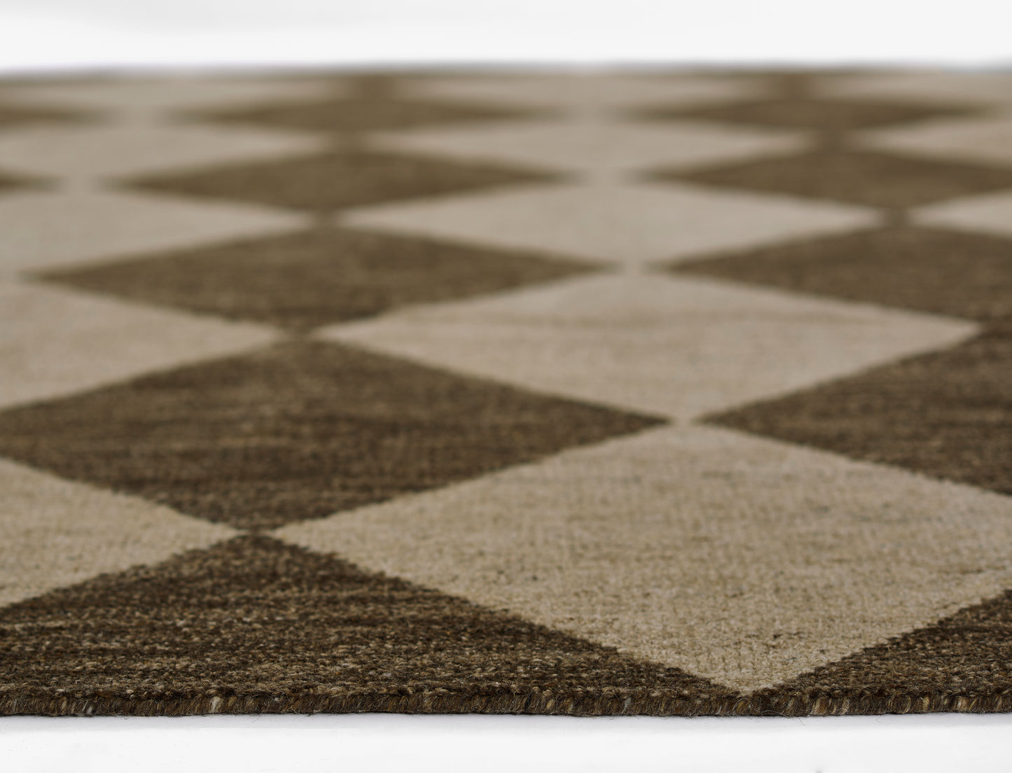 Close-up of a brown and tan diamond-pattern rug with a woven texture.