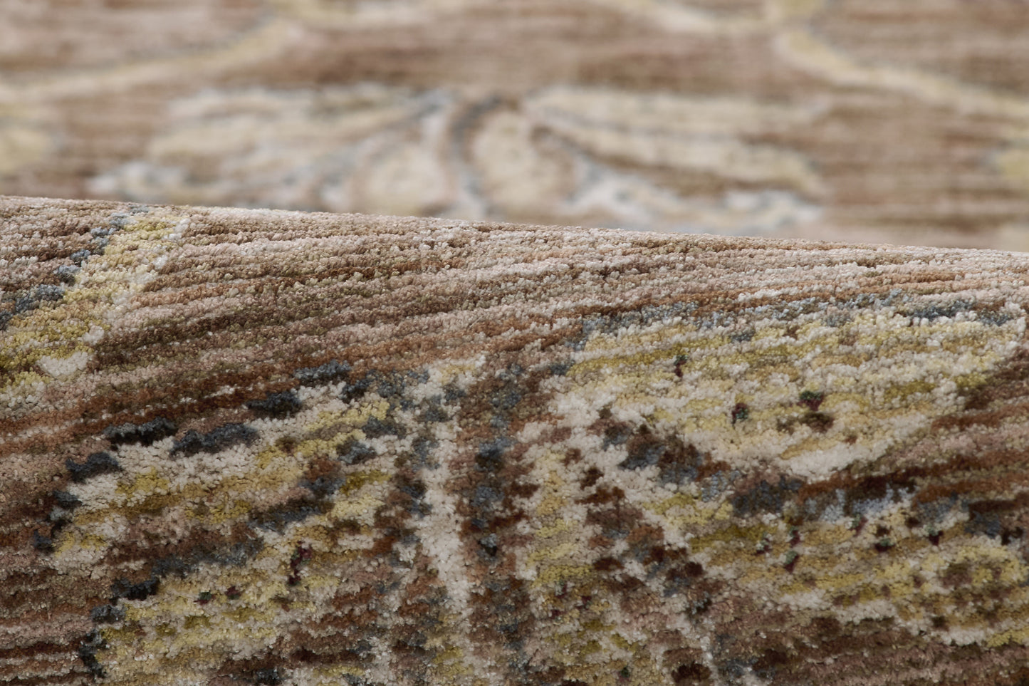 Close-up of a brown-beige oriental rug with cream and gold floral motifs and a soft plush pile.