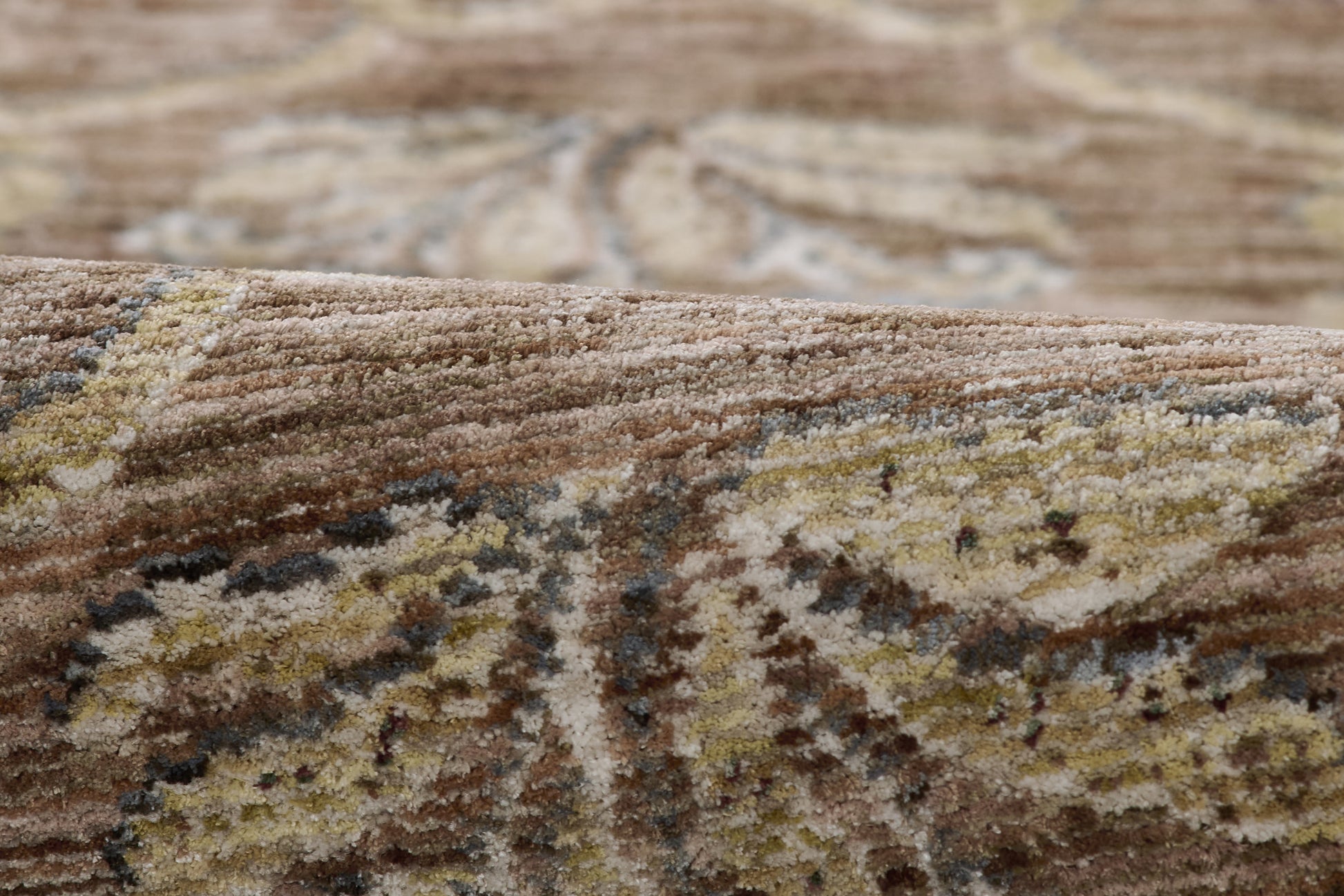 Close-up of a brown-beige oriental rug with cream and gold floral motifs and a soft plush pile.