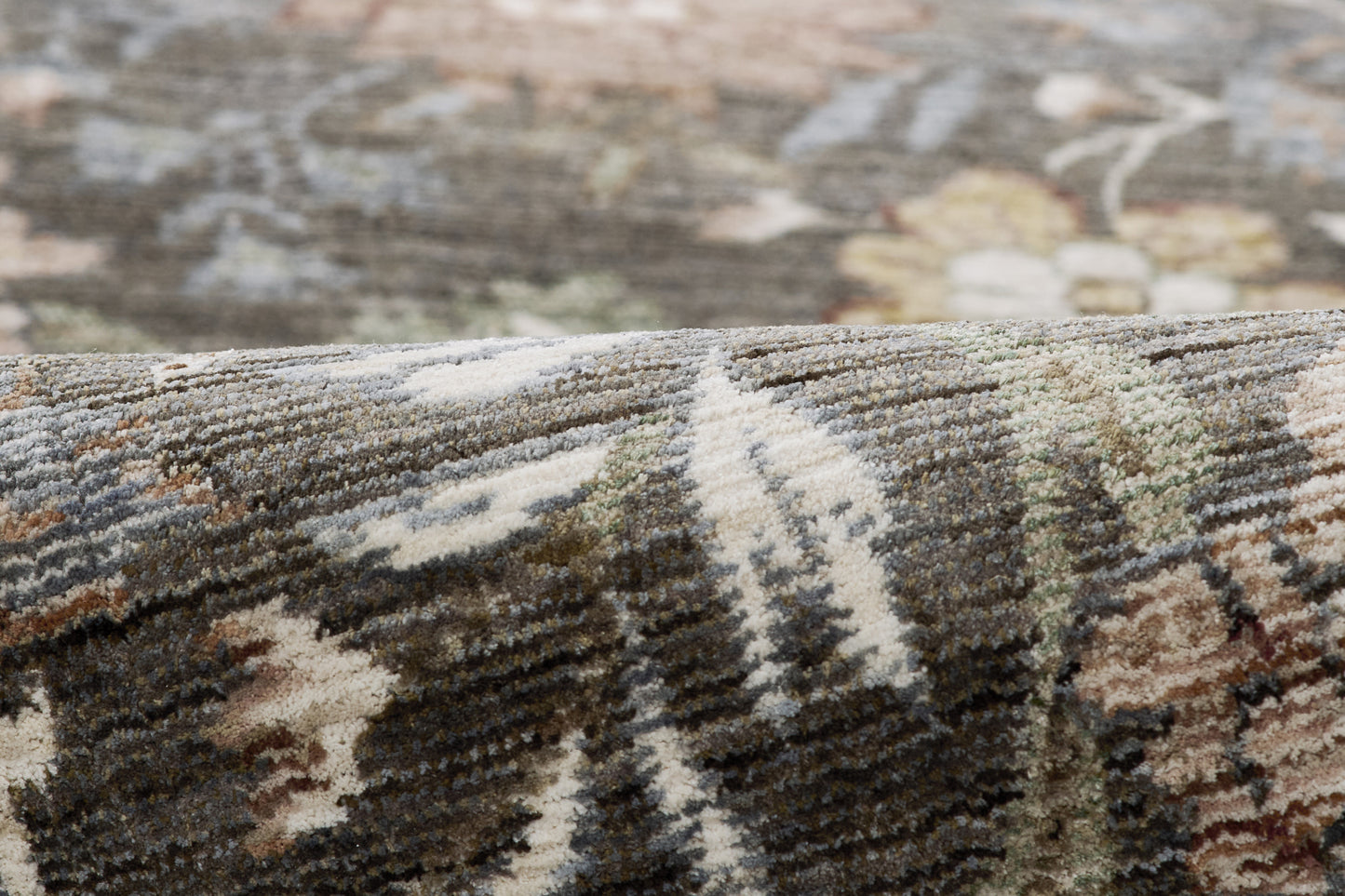 Close-up of a patterned woven rug in gray, cream, beige and brown with a folded edge.