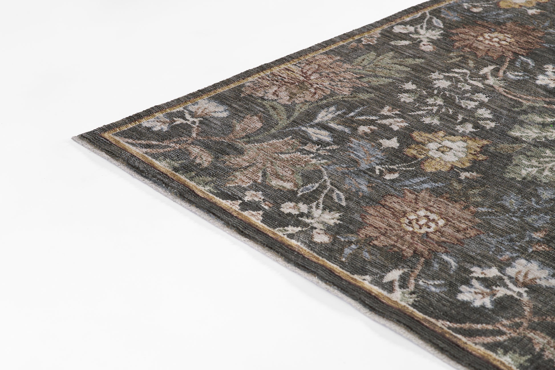 Corner of a Persian-style floral rug in muted browns, greens, and ivory; woven decorative area rug.