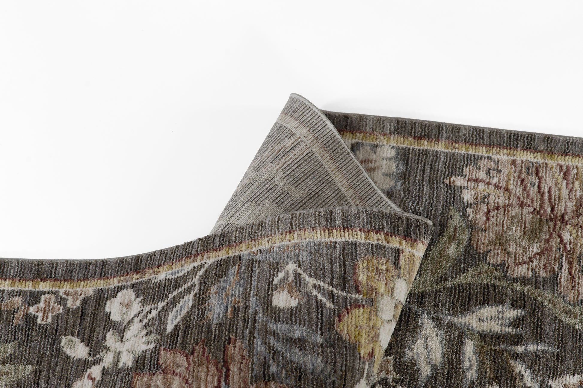 Dark floral woven rug with muted browns, beiges, maroons & greens; thick wool pile & folded corner.