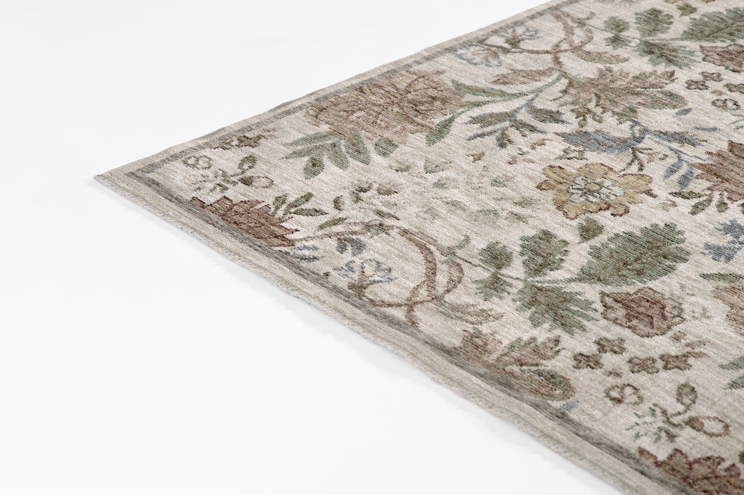 Corner of an ivory floral runner rug with muted greens, browns & blues in an antique ivy pattern.