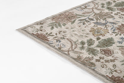 Corner of an ivory floral runner rug with muted greens, browns & blues in an antique ivy pattern.