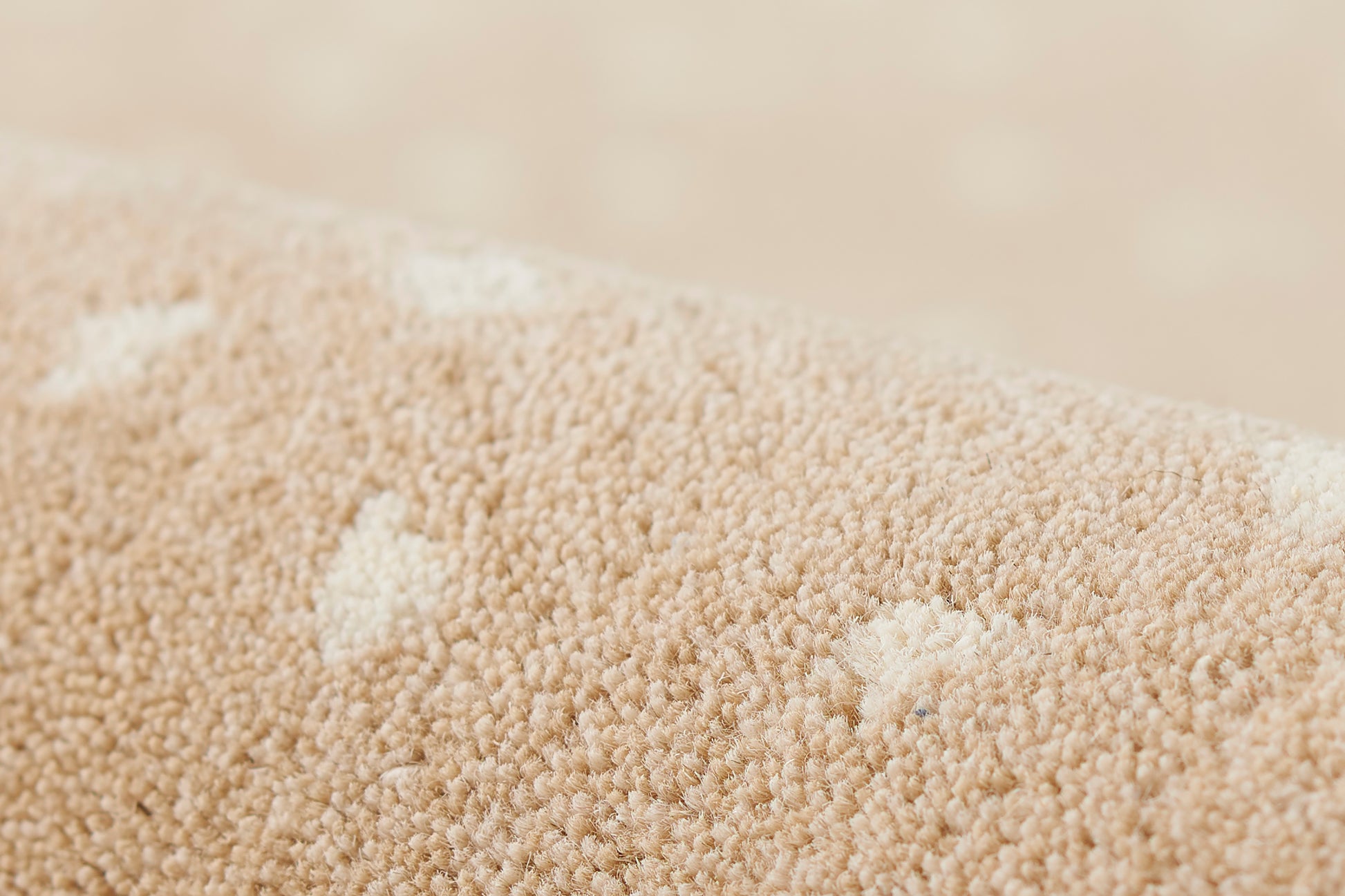 Close-up of beige rug fibers with a wood-look texture, forming a soft pile.