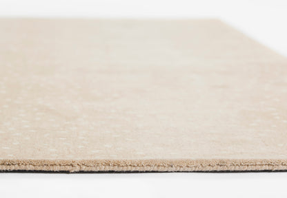 Close-up of a light beige rug edge with visible fibers.