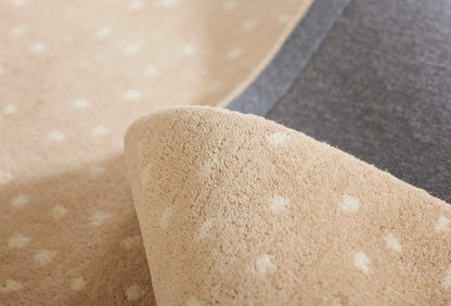 Soft beige polka-dot rug with white dots, rolled to reveal grey backing and plush textured surface.