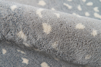 Blue-gray plush rug with cream spots, soft loop-pile texture, rolled for display.