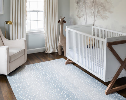 Blue Antelope rug, 10' x 14', on the nursery floor with a beige armchair, gold lamp and a giraffe plush.