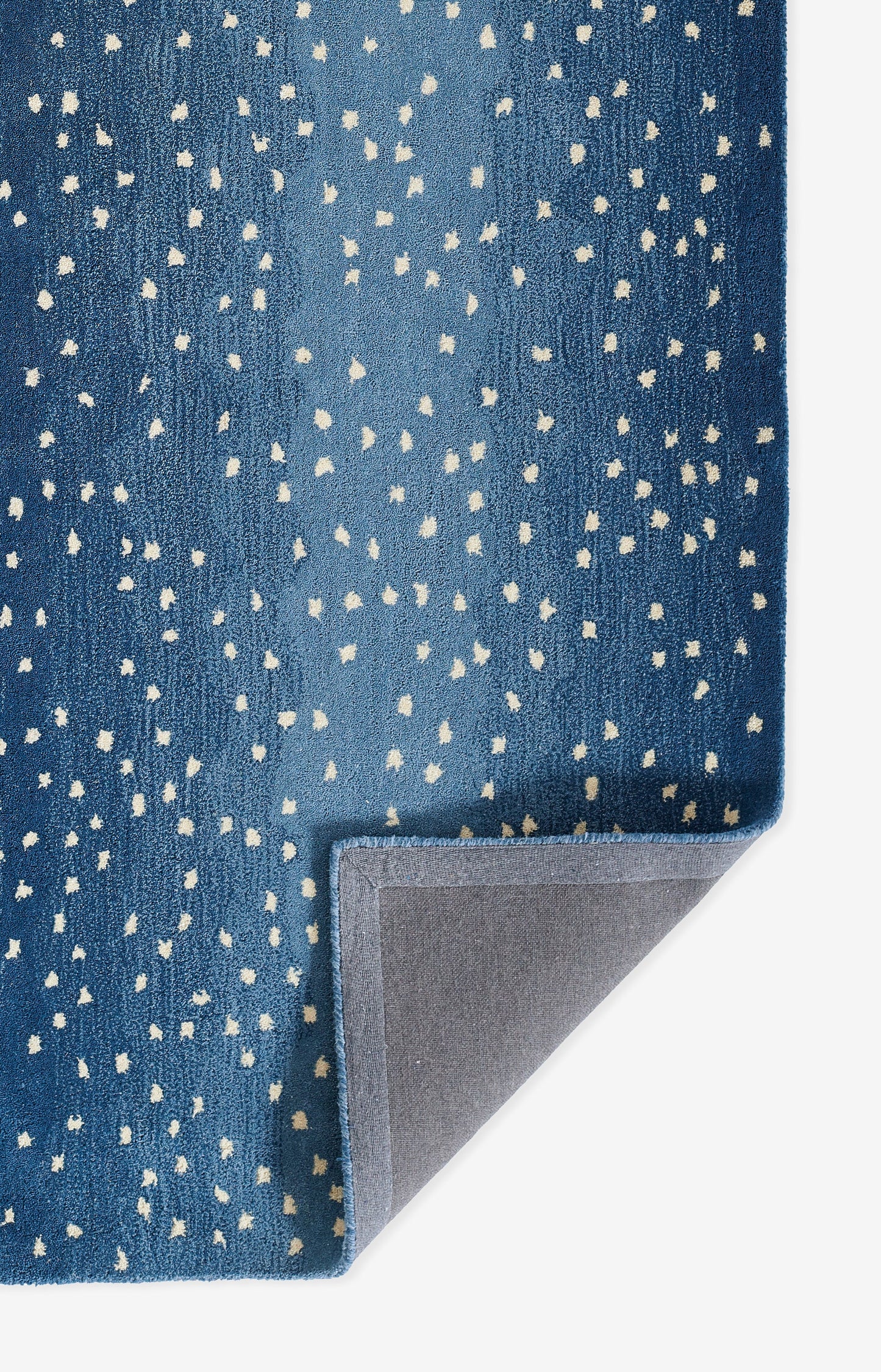 Blue speckled runner rug with white dot pattern, plush pile and gray underside visible at a folded corner.