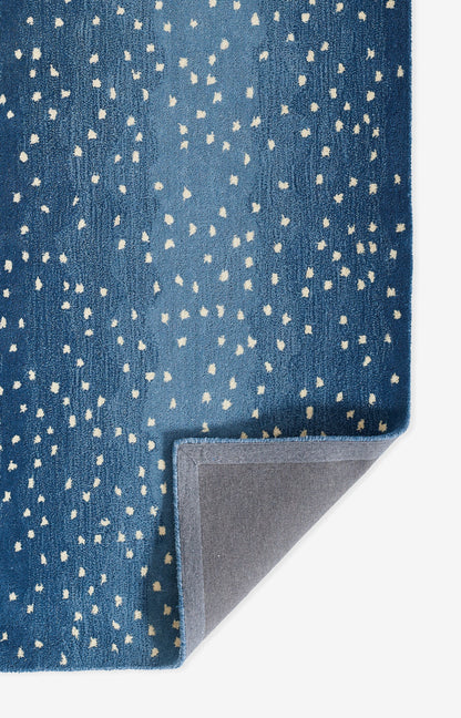 Blue speckled runner rug with white dot pattern, plush pile and gray underside visible at a folded corner.
