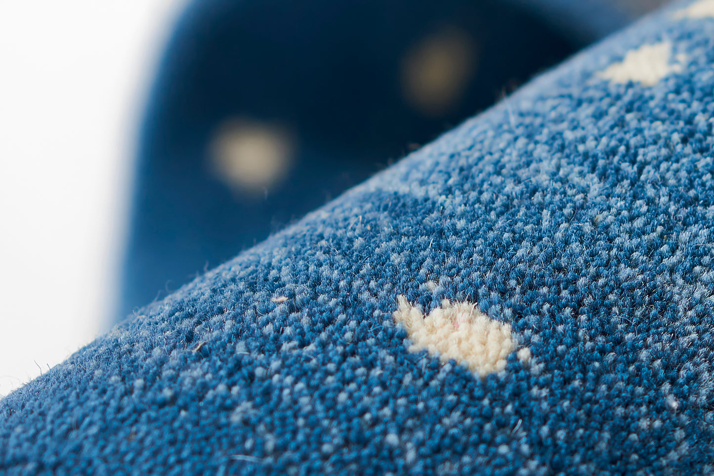 Close-up of a blue rug with a textured weave and white specks (2' x 3').