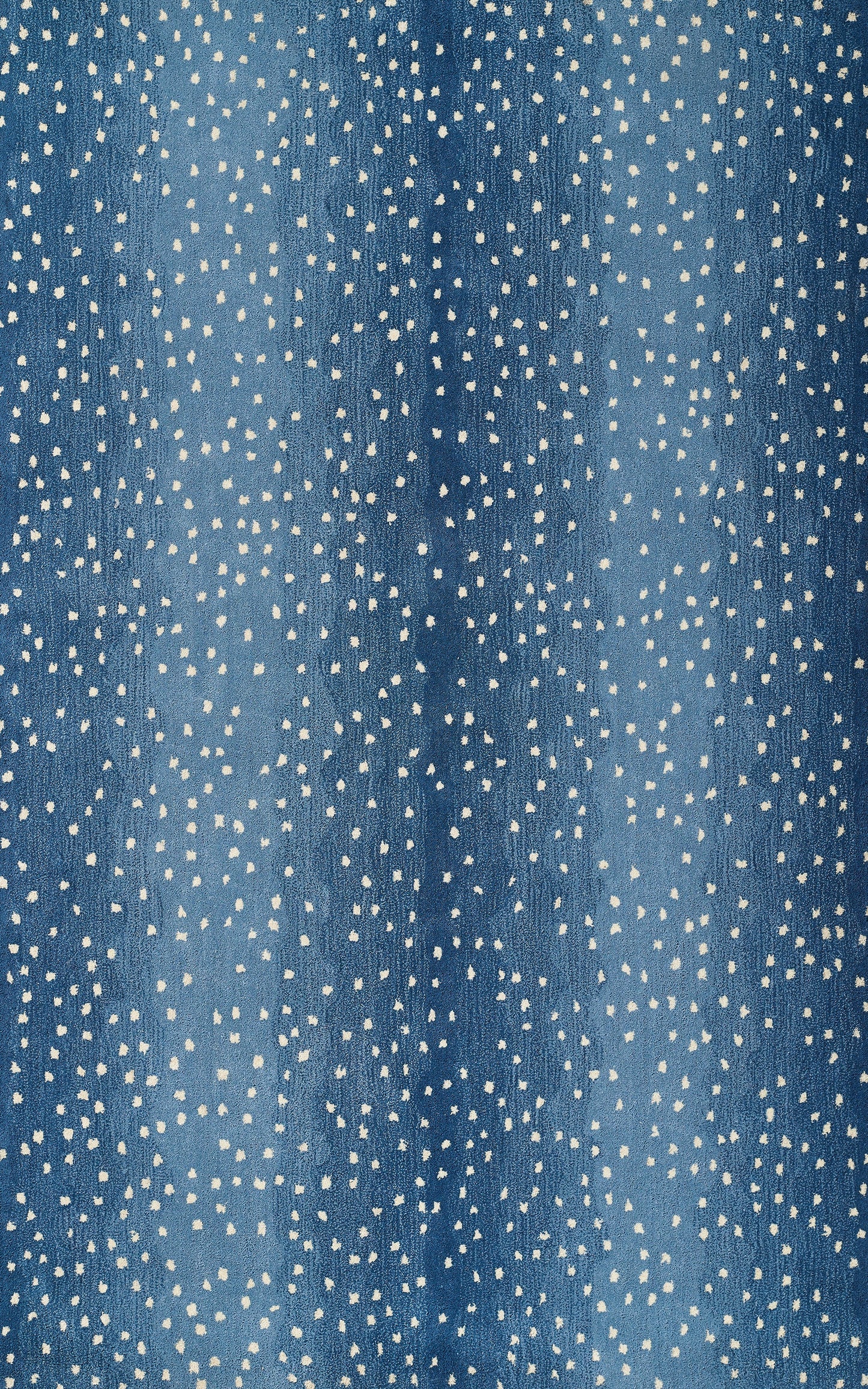 Blue denim-like fabric with irregular white speckle dots, casual speckled textile pattern.