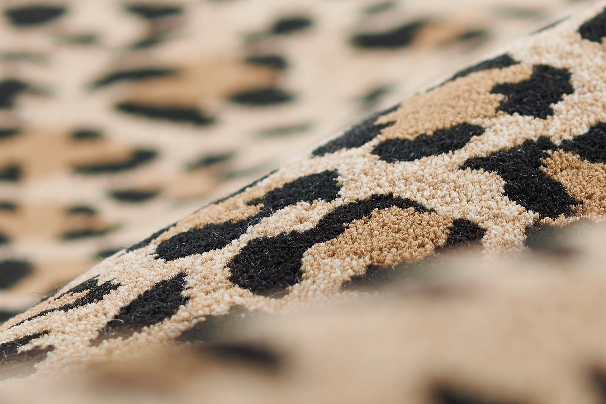 Close-up of a beige leopard-print rug with black spots and plush pile.