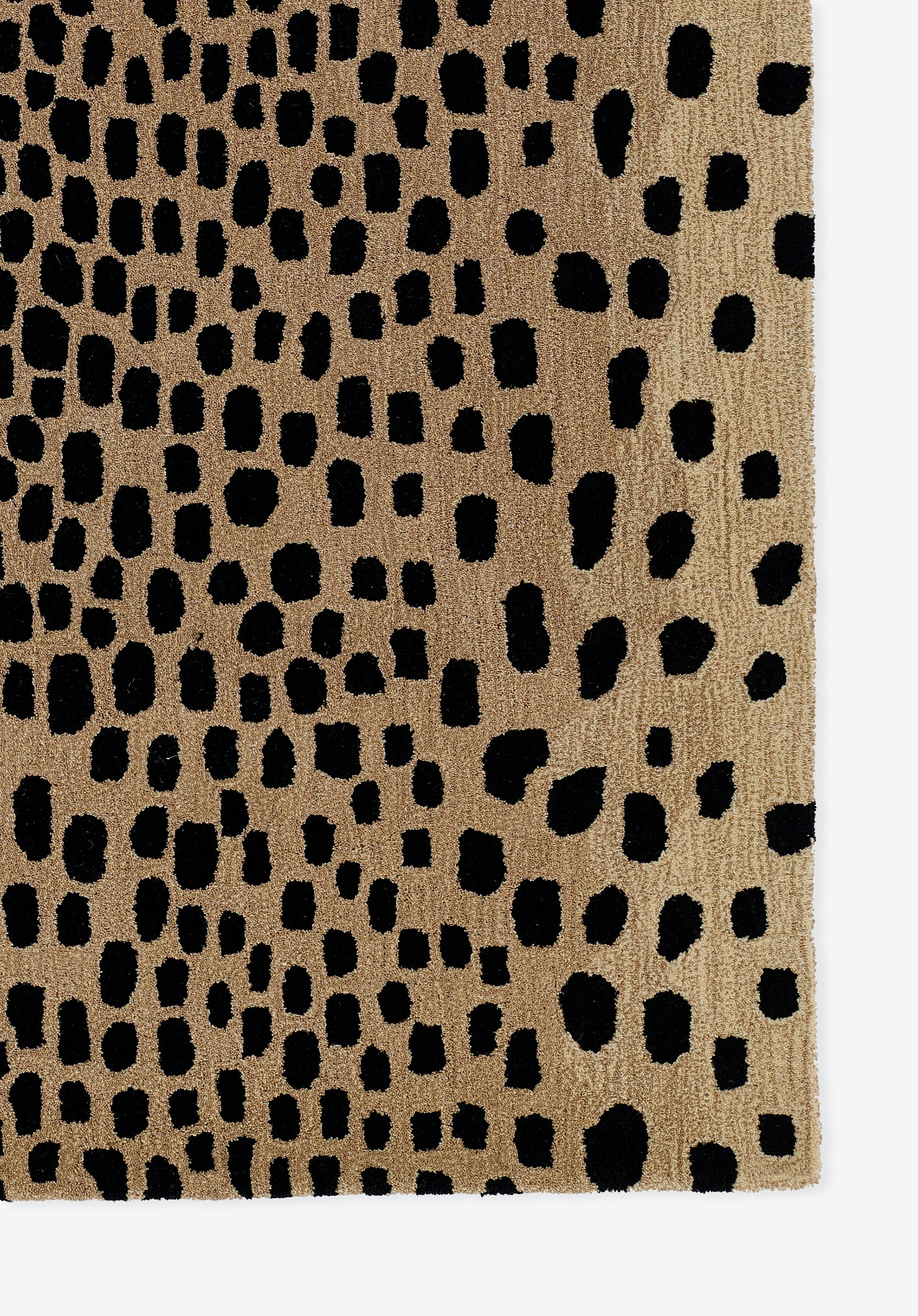 Beige textured rug with scattered black irregular dots; abstract cheetah print, rectangular floor covering for rooms.
