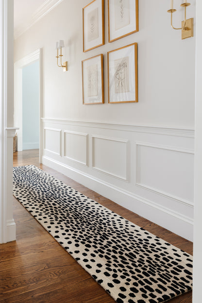 Cheetah print rug, 2' x 3', laid on a hardwood hallway floor with white wainscoting and gold-framed art.