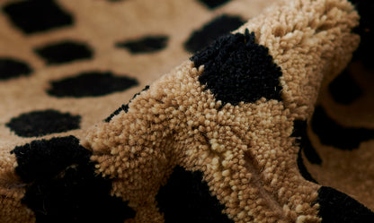 Beige cheetah-print shag rug with black spots and thick tufted pile.