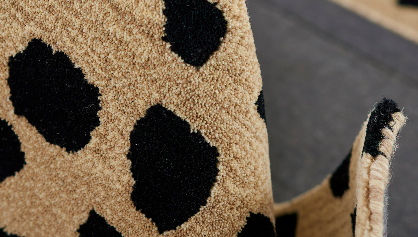 Beige shag rug with bold black cheetah spots; dense loop pile, rolled edges.