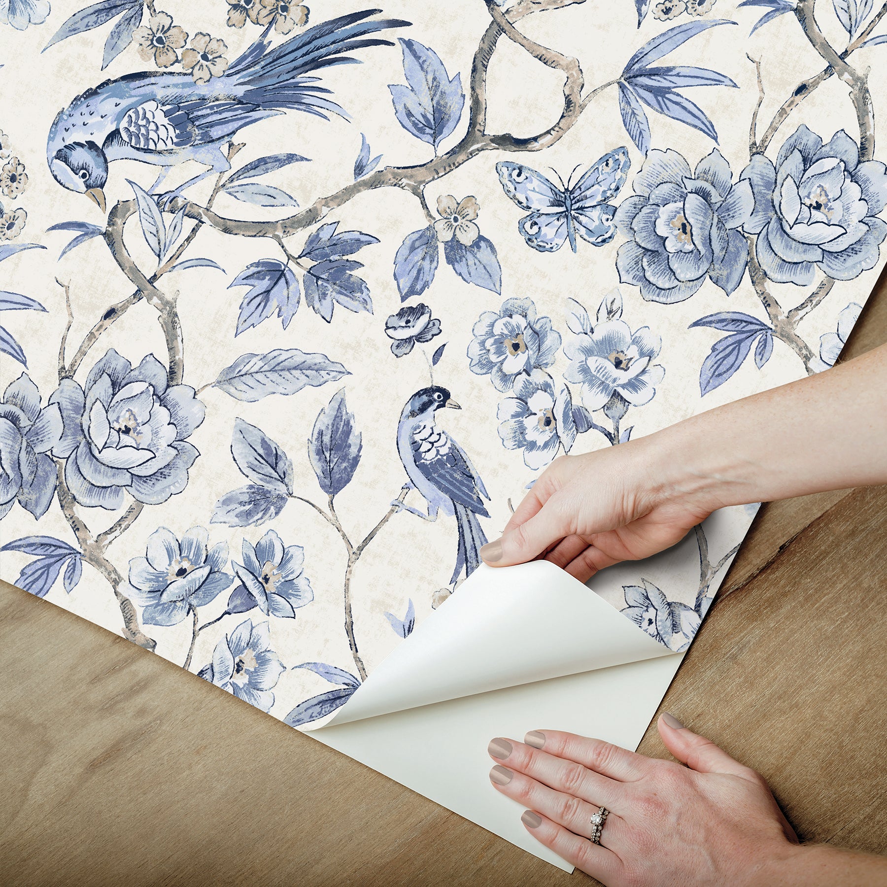 Blue floral wallpaper with birds on a cream background, shown being peeled back.