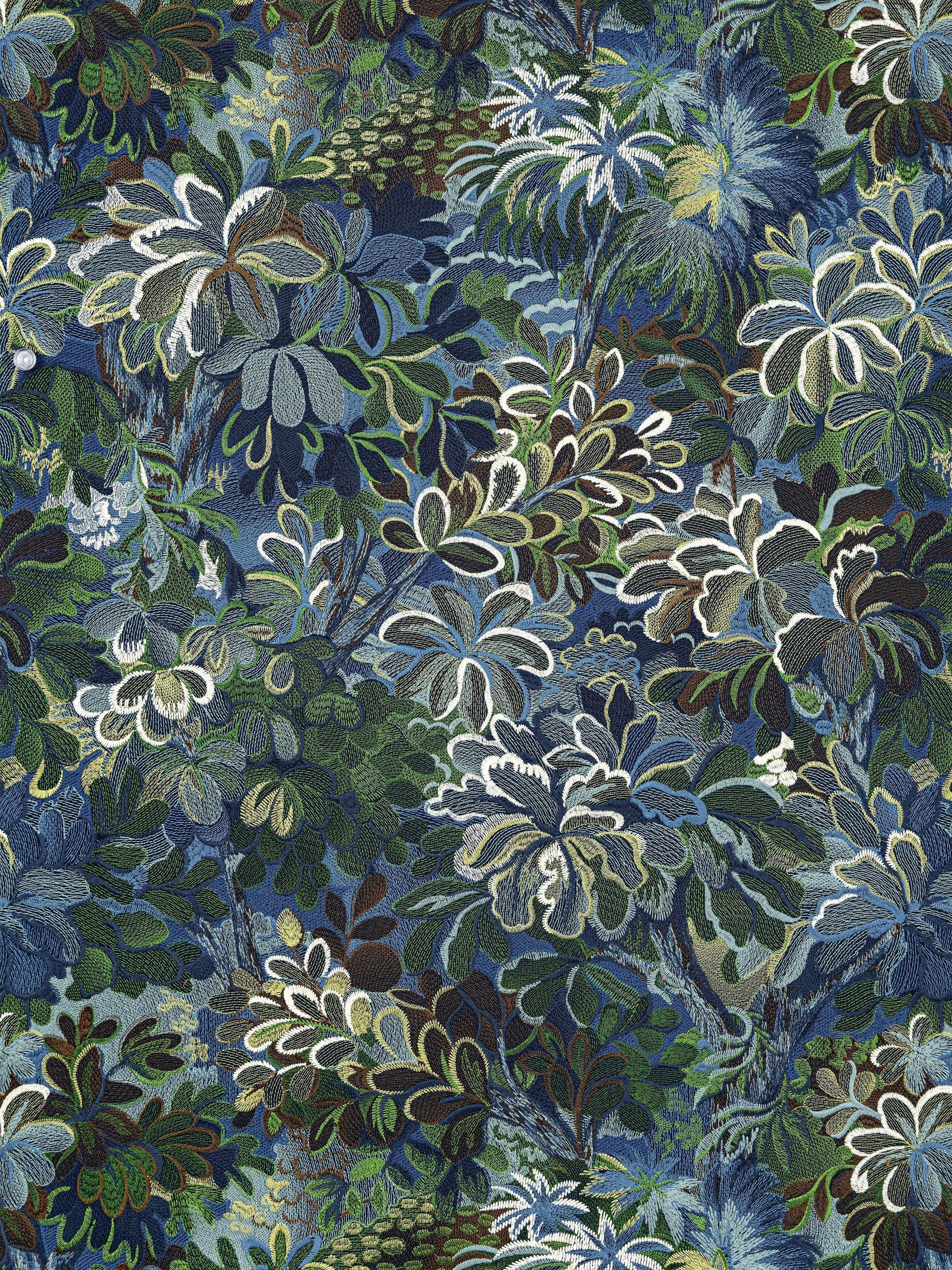 Dense tropical foliage print with blue, green and white leaves in a layered botanical pattern.