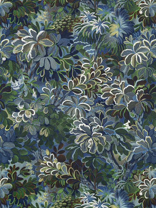 Dense tropical foliage print with blue, green and white leaves in a layered botanical pattern.
