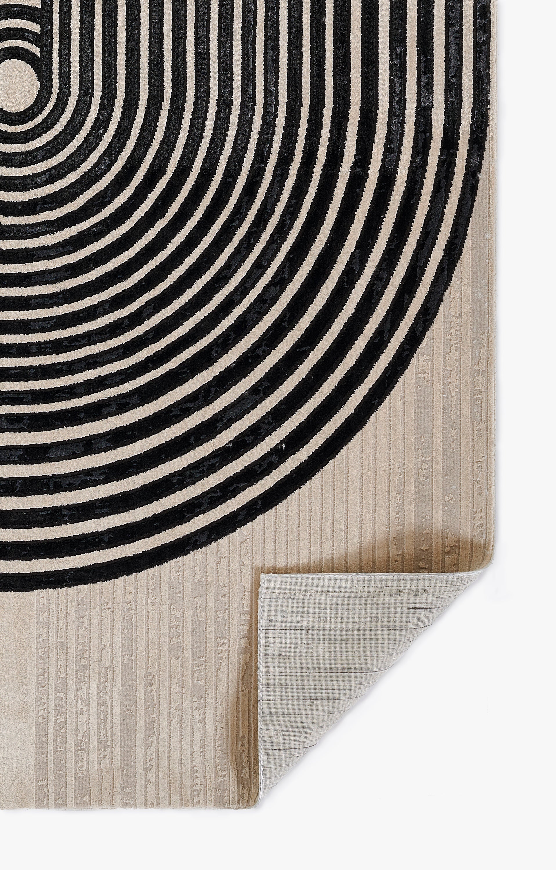 Beige woven runner rug with bold black concentric circle spiral pattern; corner folded for display, modern geometric style.