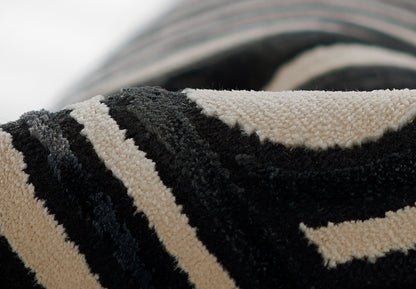 Close-up of a black and beige striped shag rug with thick looped pile, rolled edge.