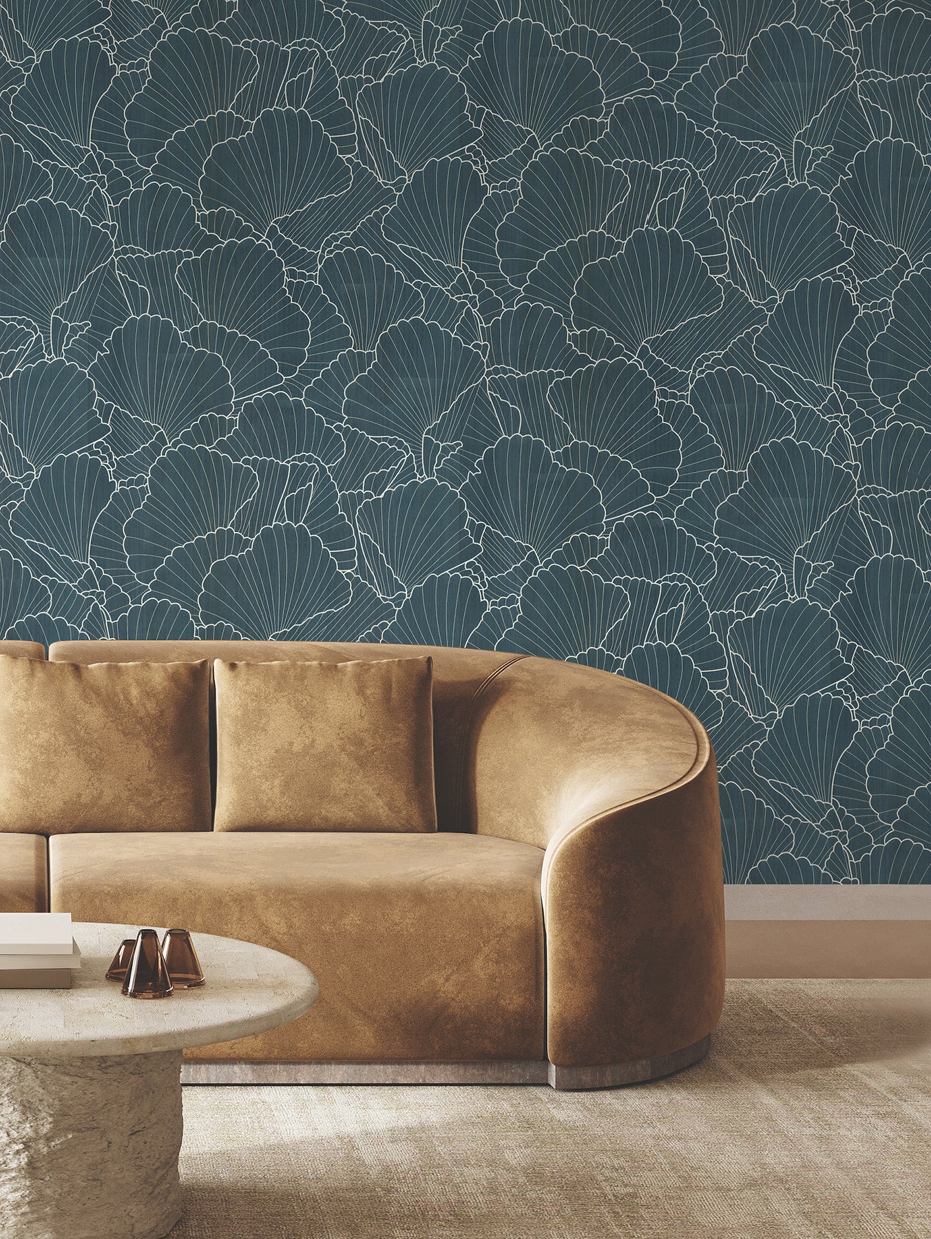 Teal botanical wallpaper with white ginkgo leaf outlines, paired with a curved tan leather sofa and round stone coffee table.