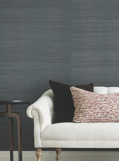 Blue-gray denim grasscloth wallpaper with a natural woven texture on the wall.