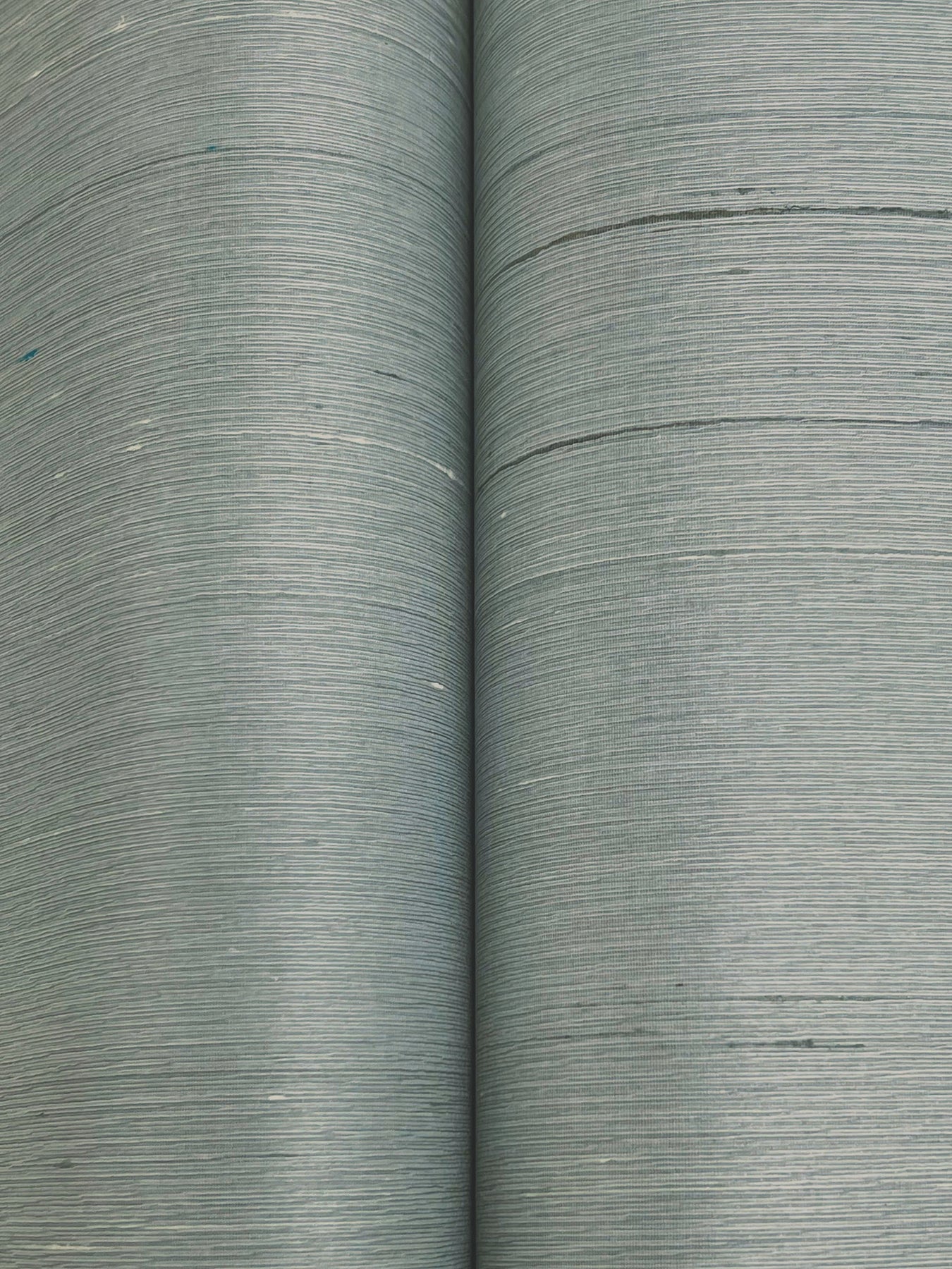 Two rolls of dusty blue wallpaper with a subtle woven texture.