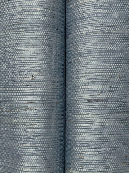 Close-up of two blue-gray grasscloth wallpaper samples showing a tight woven grid texture & subtle brown specks.