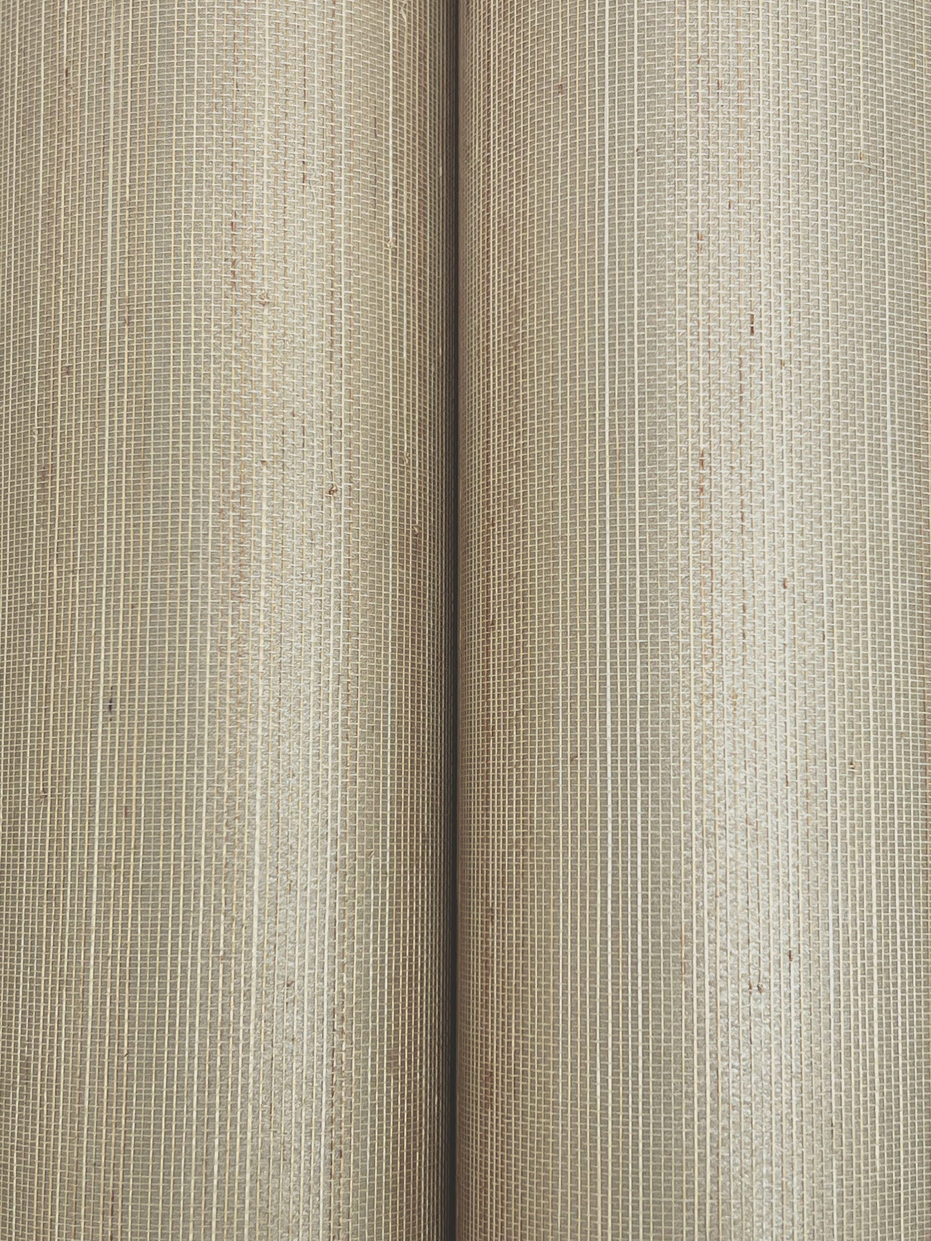 Beige natural-fiber wallpaper rolls with ribbed woven texture; rustic wallcovering detail.
