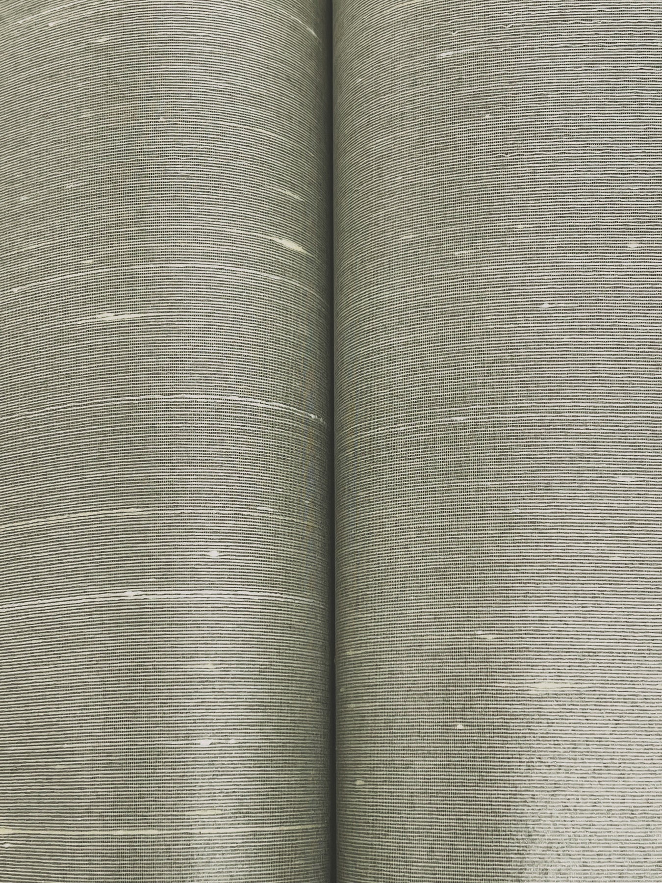 Two rolls of dove wallpaper with a woven linen-style texture and subtle white flecks.