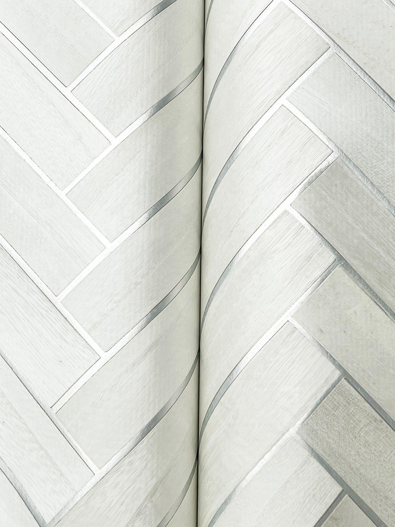 Close-up detail of pale gray herringbone wood-veneer wallpaper pattern.