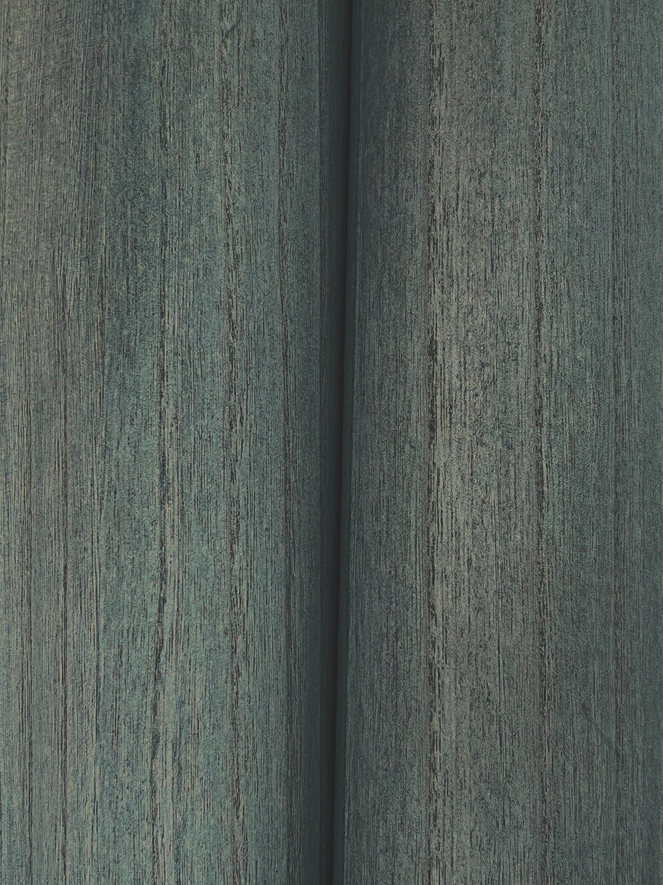 Close-up of teal wood veneer wallpaper showing weathered grain and a narrow seam.