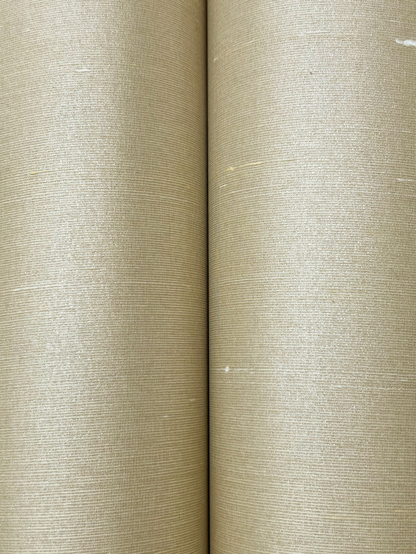 Two beige textured wallpaper rolls with linen-like weave and a center seam.