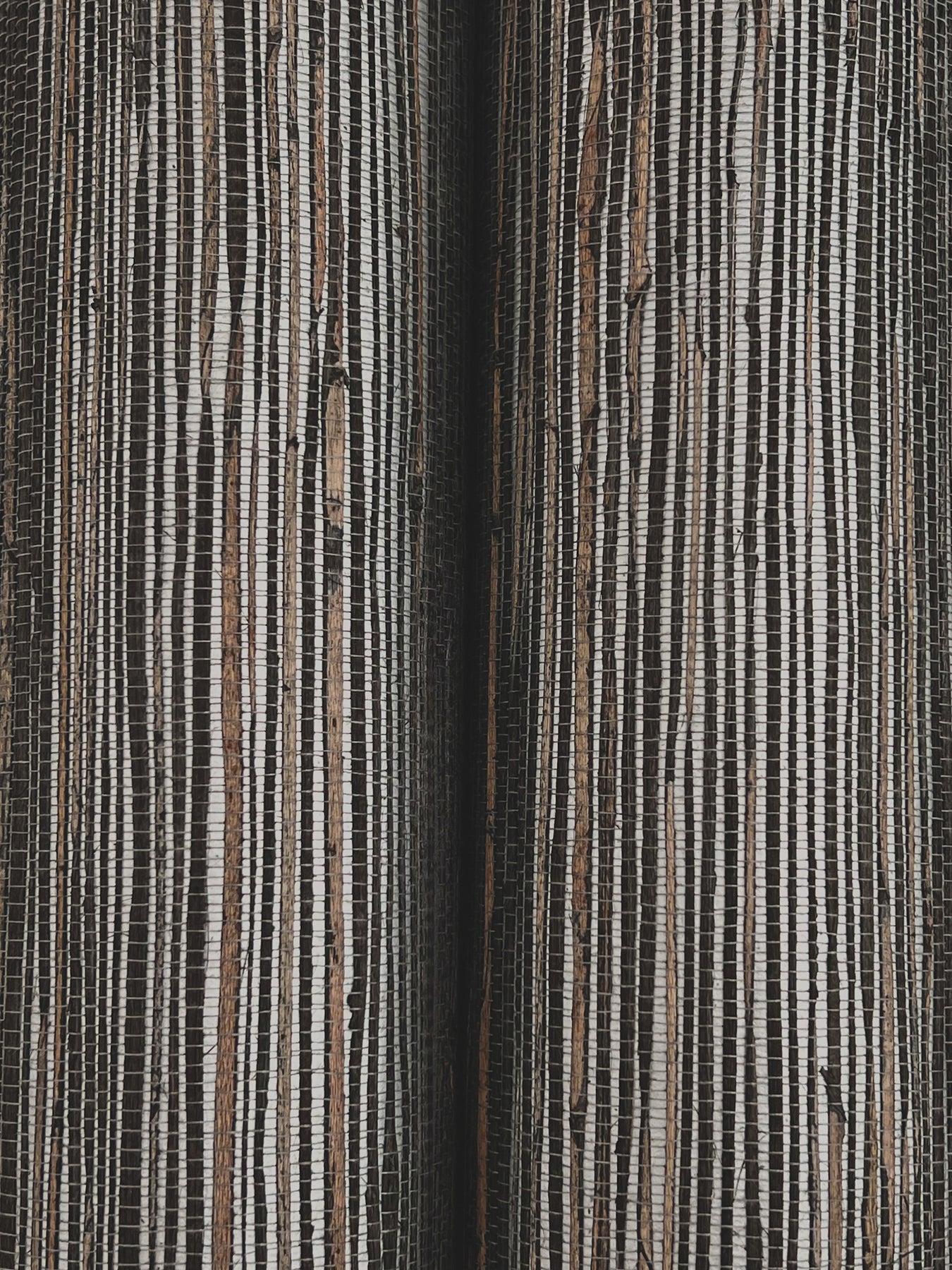 Close-up of woven grasscloth wallpaper texture in black & silver, shimmering hemp fibers with fine vertical lines.