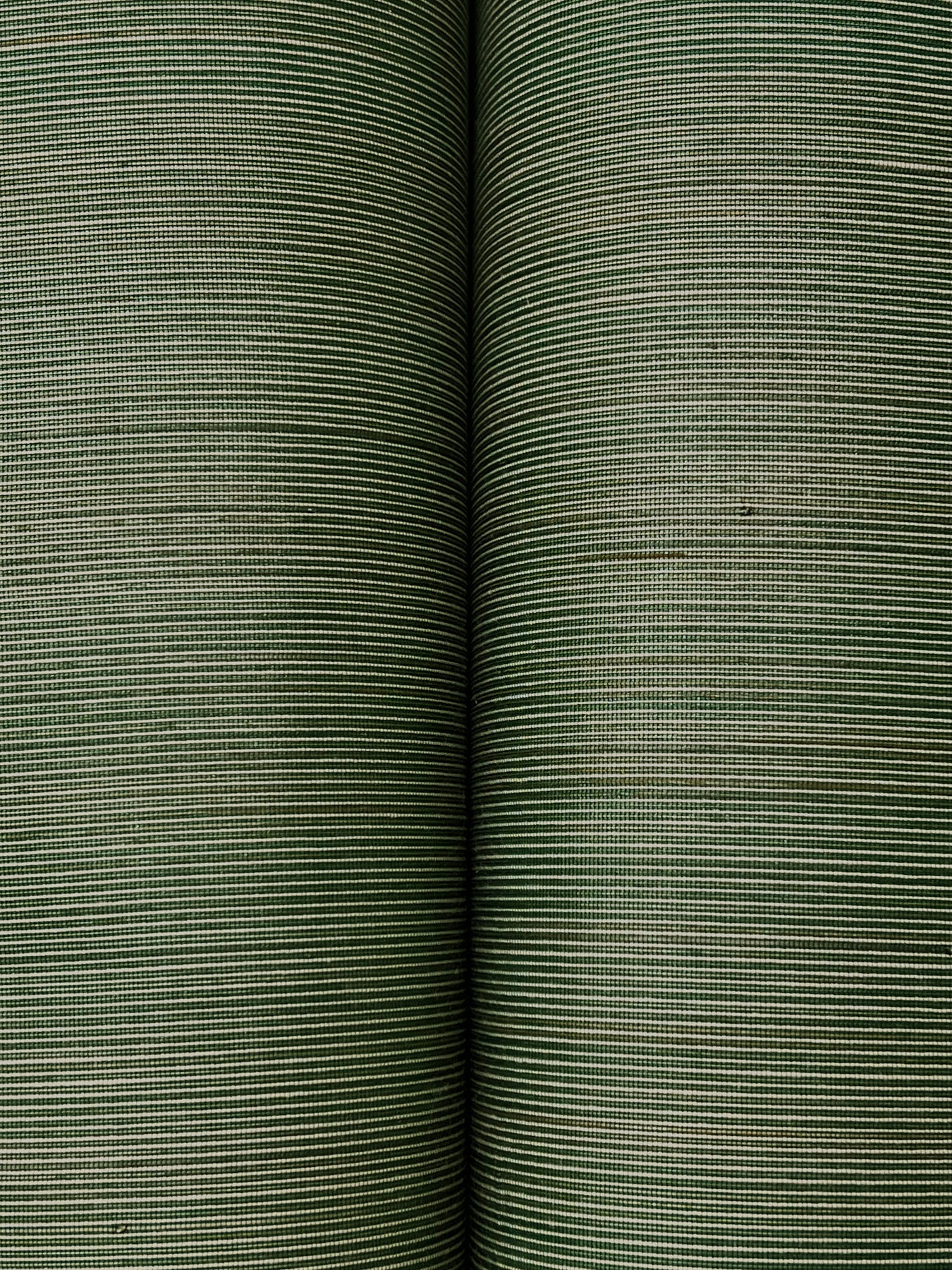 Two forest green striped wallpaper rolls with fine horizontal lines and textured grasscloth weave, close-up.
