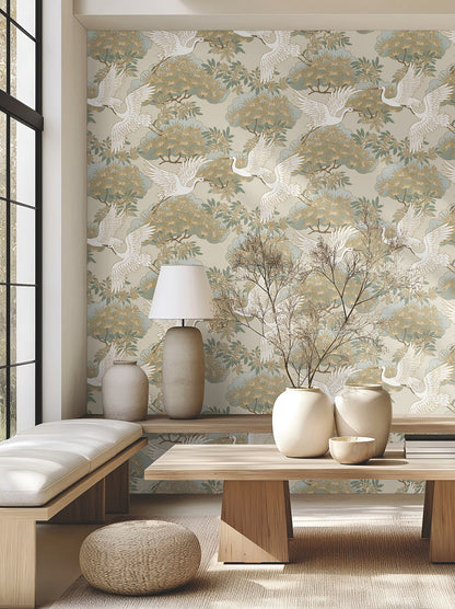 Luxury beige botanical wallpaper by Ronald Redding featuring elegant herons, ornamental bonsai trees, layered blue-green foliage, and delicate metallic gold details. Sprig & Heron wallpaper creates a peaceful, sophisticated statement wall for bedrooms, dining rooms, living spaces, offices, libraries, and upscale interior design projects.