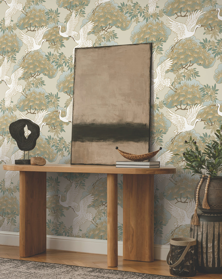 Ronald Redding Sprig & Heron Beige Wallpaper from the Tea Garden II collection by York Wallcoverings, featuring flying herons, stylized bonsai trees, botanical foliage, sand beige tones, soft greens, and metallic gold accents. Designer Chinoiserie bird wallpaper for elegant home decor, statement walls, luxury interiors, bedrooms, dining rooms, and living rooms.