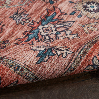 Persian-style oriental rug in red with blue and cream floral motifs, folded edge on dark wood floor.