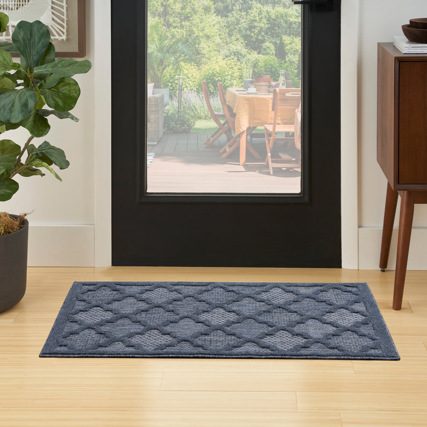 Rectangular blue tufted rug with quilted wave texture in a light-wood entryway.
