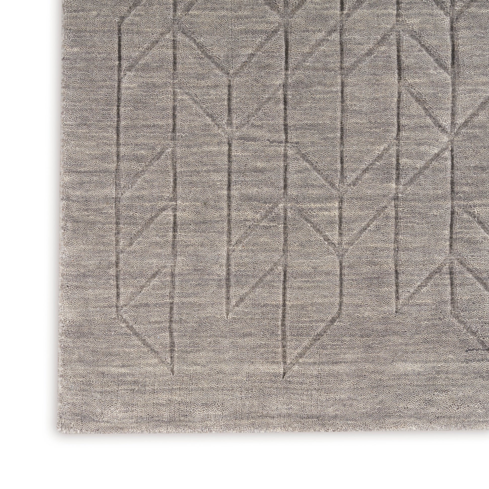 Rectangular beige rug with subtle linear geometric stitching forming chevrons along the lower edge.