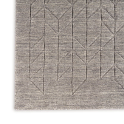 Rectangular beige rug with subtle linear geometric stitching forming chevrons along the lower edge.