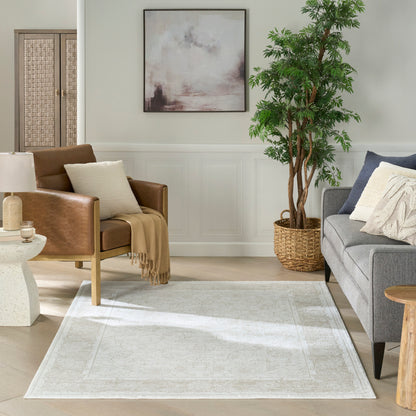Neutral area rug with subtle pattern in a light living room; gray sofa, brown leather chair, plant in woven basket, and abstract art.