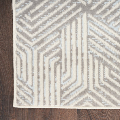 Light gray and cream geometric rug with maze-like lines, corner view on dark wood floor.
