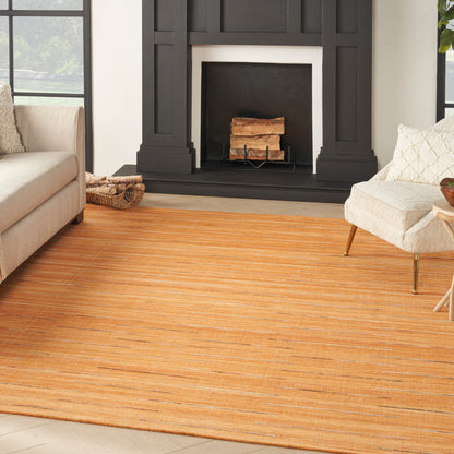 Cozy living room with orange striped rug, black fireplace, beige sofa and cream armchair on wooden floor.