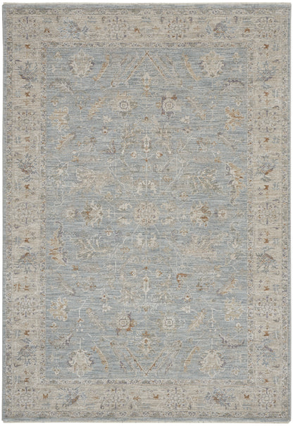 Light blue traditional area rug with ivory floral motifs and a pale beige border.